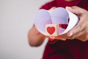 Valentijnsdag concept. persoon houdt hartvormig papier en houten kist met visueel effect. geef je liefde. foto