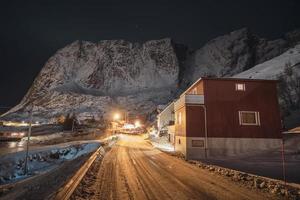 Noors dorp op landweg met licht schijnt en sneeuwbergketen foto