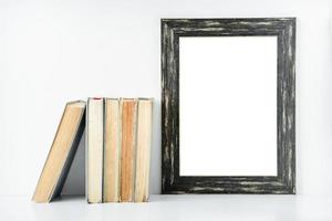 leeg zwart frame en oude boeken op een witte achtergrond. foto