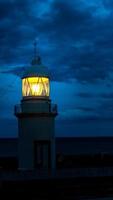 de vuurtoren gloeit in de donkere nacht aan de kust van spanje foto