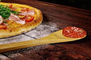 pizza op houten tafel met ingrediënten foto