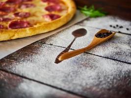 zwarte peper in een houten lepel op de keukentafel foto