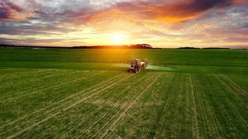 boer werkt in het veld op een tractor tot zonsondergang foto
