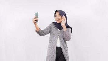 jonge Aziatische vrouw groet op smartphone gelukkig geïsoleerd op witte achtergrond foto