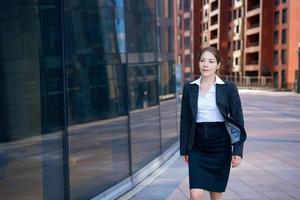 succesvolle jonge vrouw op de achtergrond van een kantoorgebouw foto