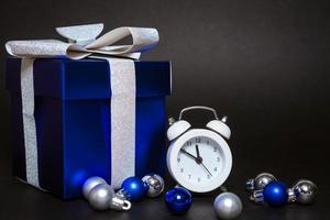 mooie blauwe geschenkdoos en witte wekker op zwarte achtergrond foto