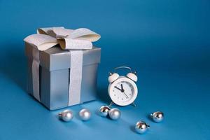 zilveren cadeau met witte wekker en kerstversiering op blauwe achtergrond foto