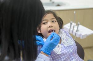 een klein schattig meisje met tanden onderzocht door tandarts in tandheelkundige kliniek, tandencontrole en gezond gebit concept foto