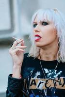 portret van stijlvolle blonde grunge jonge vrouw met make-up roken sigaret foto