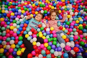 broer met zus spelen in kleurrijke ballenbak. kinderdagverblijf binnenspeeltuin. ballenbad voor kinderen. kleuterschool of voorschoolse speelkamer. foto