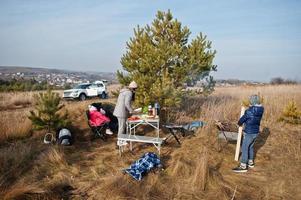 familie barbecueën op een terras in het dennenbos. bbq-dag met grill. foto