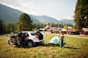 jongen zet een tent op. reizen met de auto in de bergen, sfeerconcept. foto