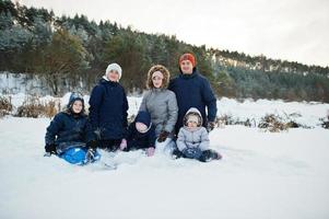 vader en moeder met vier kinderen in de winternatuur. buiten in de sneeuw. foto