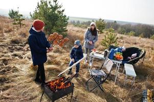 familie barbecueën op een terras in het dennenbos. bbq-dag met grill. foto