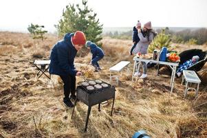 familie barbecueën op een terras in het dennenbos. bbq-dag met grill. foto