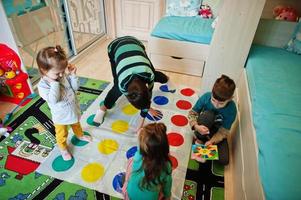 gelukkige familie die samen plezier heeft, vier kinderen die thuis een twister-spel spelen. foto