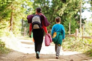 achterkant van moeder met drie kinderen die op houten bergen lopen. familie reizen en wandelen met kinderen. foto