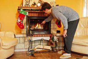 man thuis bij een open haard in warme woonkamer op winterdag. foto