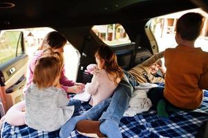 moeder met vier kinderen bij voertuiginterieur. kinderen in de kofferbak. reizen met de auto, liegen en plezier maken, sfeerconcept. foto