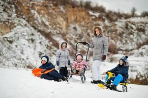 familie speelt en sleeën in de winter buiten, moeder en kinderen hebben plezier. foto