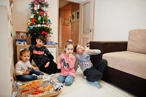 gelukkig gezin met vier kinderen die thuis pizza eten. foto