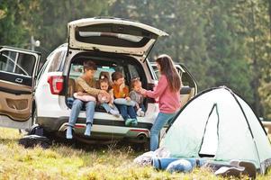 gezin van vier kinderen en moeder bij voertuiginterieur. kinderen zitten in de kofferbak. reizen met de auto in de bergen, sfeerconcept. foto