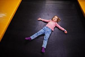 schattig babymeisje liggend op een trampoline in indoor speelcentrum. foto