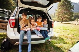 gezin van vier kinderen in het interieur van het voertuig. kinderen zitten in de kofferbak. reizen met de auto in de bergen, sfeerconcept. foto