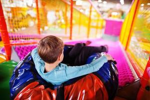 gelukkige jongen zitten in buizen donuts genieten van dia's in leuk kindercentrum. foto