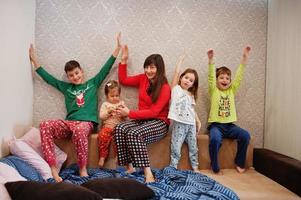 gelukkige grote familie heeft samen plezier in de slaapkamer. grote familie ochtend concept. moeder met vier kinderen draagt thuis een pyjama in bed. foto