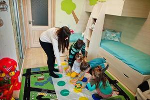 gelukkige familie die samen plezier heeft, vier kinderen en moeder die thuis een twister-spel spelen. foto