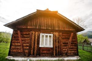 antiek houten huis met één raam op zonsondergang foto