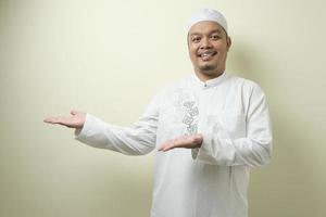 portret van een Aziatische jonge moslimman die lacht en wijst naar iets aan zijn zijde te presenteren foto