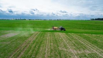 luchtfoto, boer op tractor met sproeier maakt mest voor jonge groenten foto