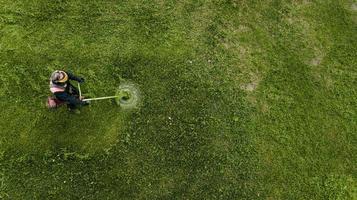 bovenaanzicht man werknemer gras maaien met grasmaaier. foto