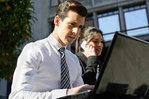 jonge zakenman typen in een laptopcomputer in stedelijke achtergrond foto
