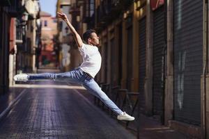 gelukkige zwarte man doet een acrobatische sprong in het midden van de straat. foto