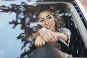 jonge Arabische vrouw in een witte auto die door het raam kijkt foto