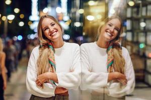blond meisje lacht 's nachts met onscherpe stadslichten foto