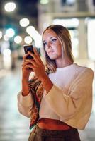 vrouw die 's nachts op straat foto's maakt met smartphone foto