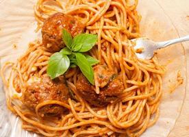 huisgemaakte spaghetti en gehaktballen in tomatensaus met verse basilicum erop foto
