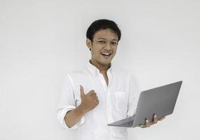 jonge aziatische man lacht en geniet wanneer hij thuis werkt met een laptopcomputer. werk vanuit huis concept. foto