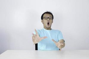 wow en geschokt gezicht van jonge aziatische man met open handgebaar. reclame model concept met blauw shirt. foto