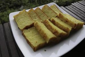 bika ambon, indonesische cake met vierkante plakjes in witte plaat. gele cake uit medan, indonesië. foto