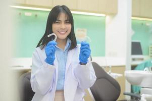 jonge vrouwelijke tandarts met invisalign in tandheelkundige kliniek, tandencontrole en gezond gebit concept foto