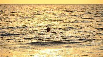 documentatie van surfers in actie in de schemering met een gouden kleur en donker, ongericht en donker op het strand van Senggigi Lombok, West Nusa Tenggara Indonesië, 27 november 2019 foto