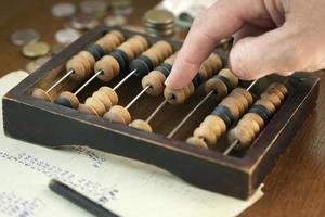 mannenhand geld tellen met vintage houten telraam foto