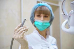 een vrouwelijke tandarts houdt een boormachine in haar hand foto