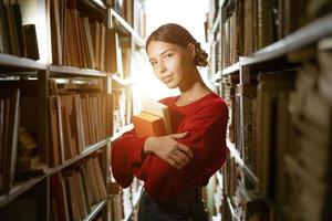 het meisje houdt een boek in haar handen tegen de achtergrond van de bibliotheek. foto