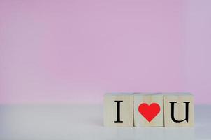 houten kubussen met ik hou van je symbool hart op de roze achtergrond en kopieer ruimte. foto
